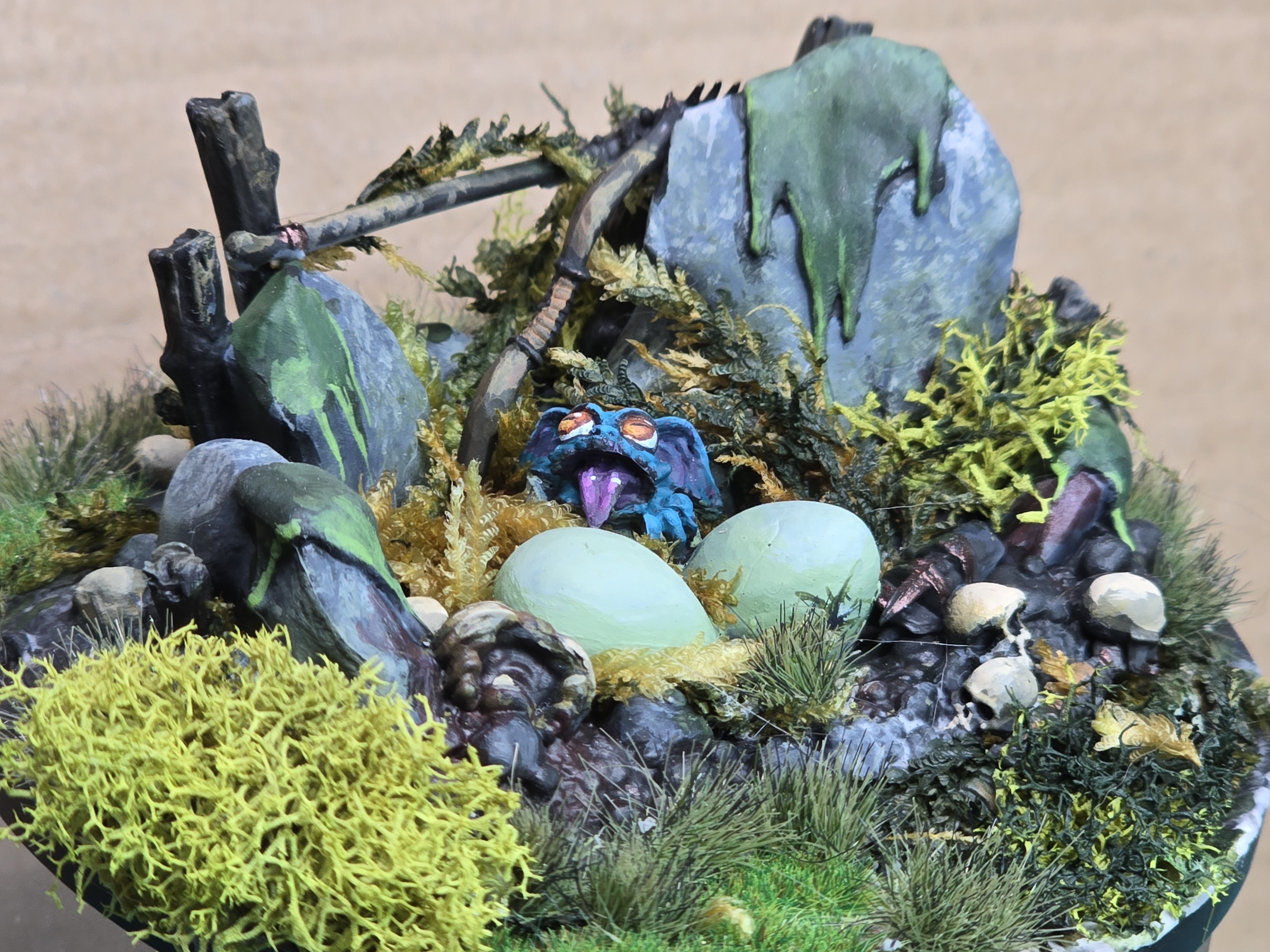 A blue hatchling troll, still in the nest. Beside it, two other eggs are starting to hatch..